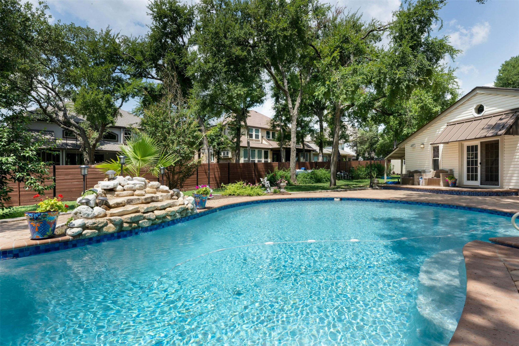 9911 Anderson Mill Road Austin, TX 78750 - Photo 24 of 29 An inviting backyard oasis awaits with a sparkling pool and a charming rock waterfall feature.