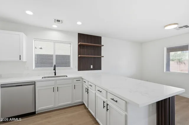 a kitchen with a sink dishwasher and white cabinets with wooden floor