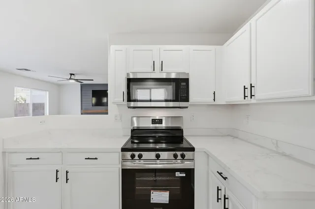 a kitchen with stainless steel appliances a stove and white cabinets