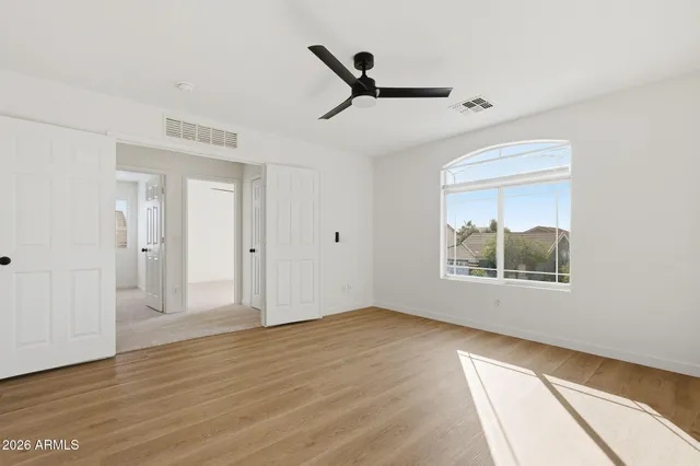 a view of empty room with wooden floor and fan