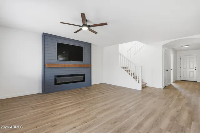 a view of empty room with wooden floor and fan