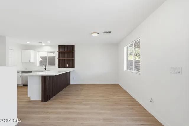 a large white kitchen with kitchen island a sink dishwasher a stove and a refrigerator with wooden floor