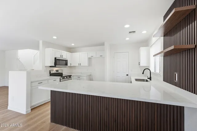 a kitchen with stainless steel appliances a sink dishwasher a refrigerator and a stove with wooden floor