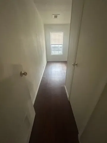 a view of a hallway with wooden floor and closet
