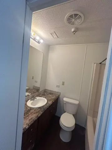 a bathroom with a granite countertop toilet sink and mirror