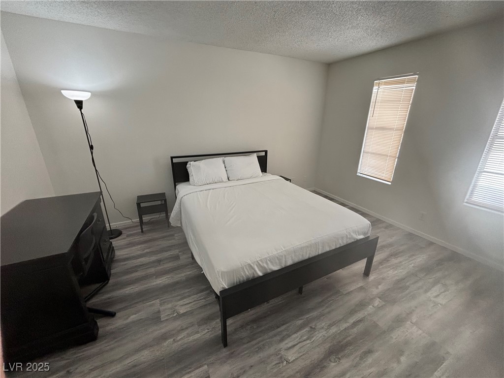 Bedroom featuring wood finished floors, a textured ceiling, and baseboards