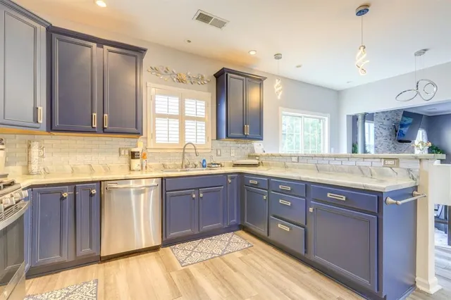 a large kitchen with kitchen island granite countertop wooden cabinets a sink and dishwasher