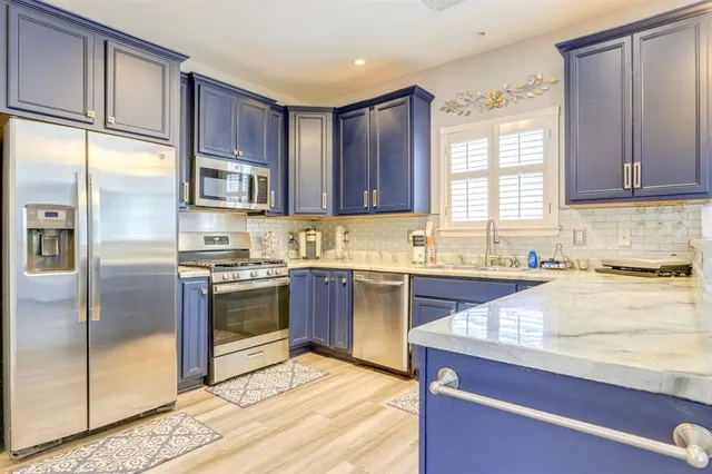 a kitchen with stainless steel appliances granite countertop a refrigerator a sink a stove and cabinets