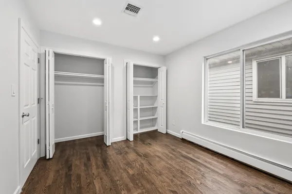 an empty room with wooden floor closet and windows