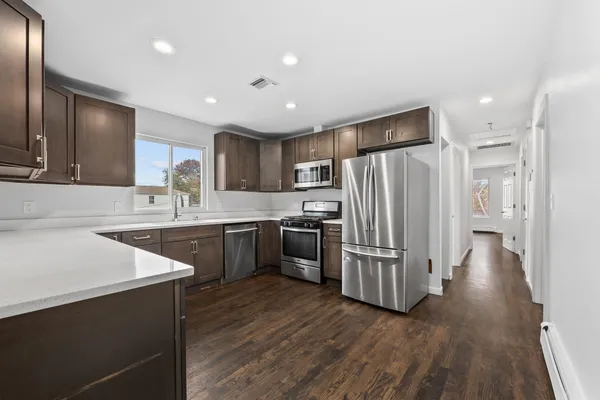 a kitchen with stainless steel appliances a refrigerator a sink dishwasher a stove top oven a refrigerator with wooden floors