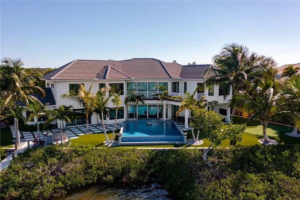 a view of a house with swimming pool lawn chairs and a yard