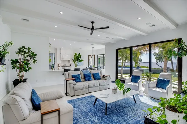 a large white kitchen with stainless steel appliances a white table chairs a window and a potted plant