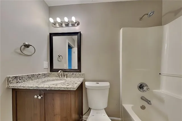 a bathroom with a granite countertop sink a toilet and shower