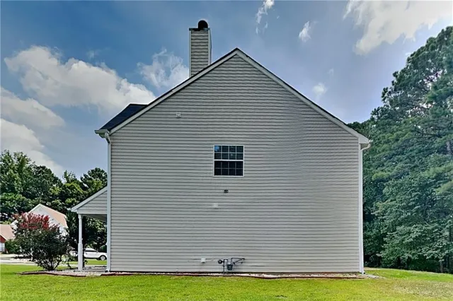 a view of a white house next to a yard with plants and trees