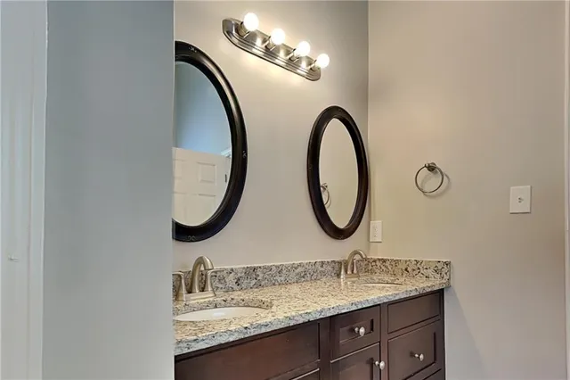 a bathroom with a granite countertop double vanity sink and a mirror