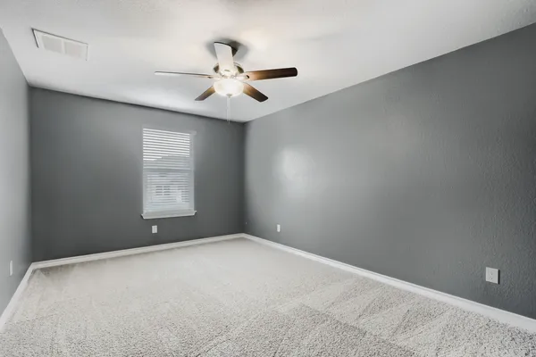 an empty room with windows and fan