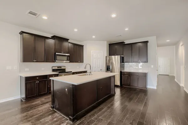 a open kitchen with stainless steel appliances granite countertop a stove top oven a sink dishwasher and a refrigerator with wooden floor