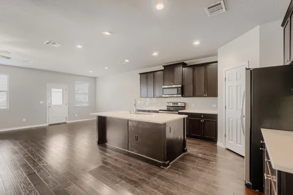 a large kitchen with stainless steel appliances granite countertop a stove a refrigerator a sink dishwasher and a oven with wooden floor