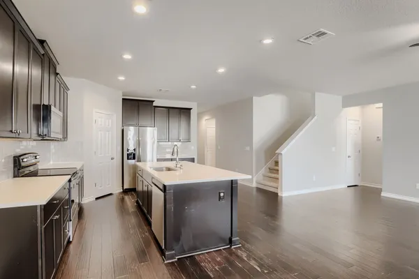 a kitchen with a sink stainless steel appliances a counter top space and cabinets