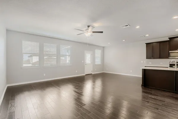 a view of an empty room with a kitchen and a window