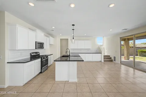 a kitchen with stainless steel appliances granite countertop a sink and a stove top oven with white cabinets