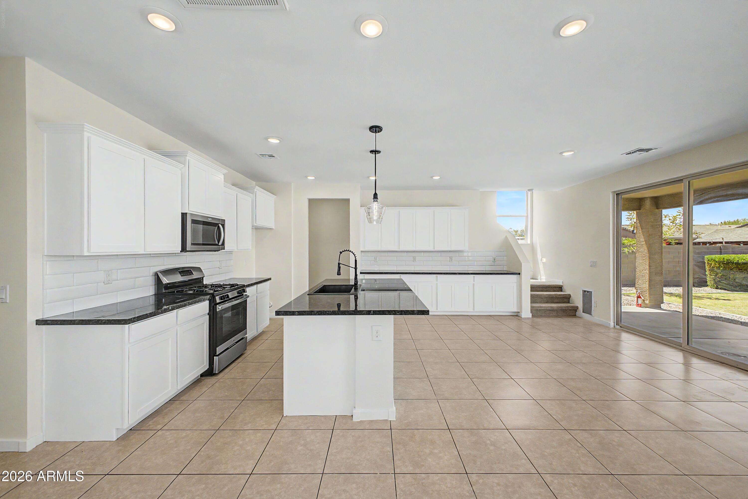 37154 North Navarra Road San Tan Valley, AZ 85140 - Photo 11 of 25 a kitchen with stainless steel appliances granite countertop a sink and a stove top oven with white cabinets