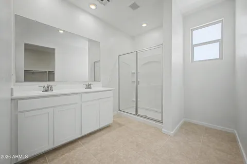 a spacious bathroom with a shower a sink and a mirror