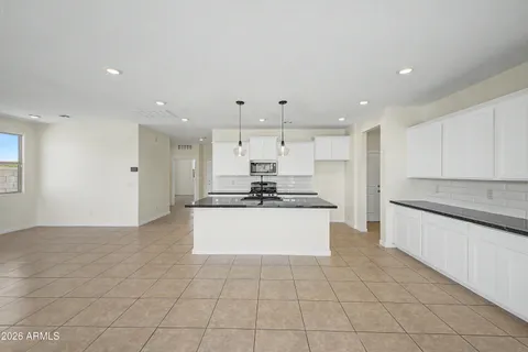 a large kitchen with granite countertop a white stove top oven and white cabinets