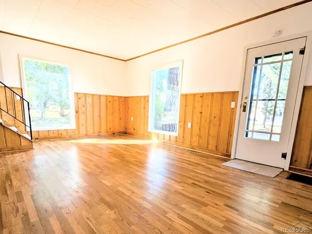 a view of an empty room with a window and wooden floor
