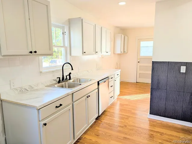 a kitchen with white cabinets a sink and wooden floor