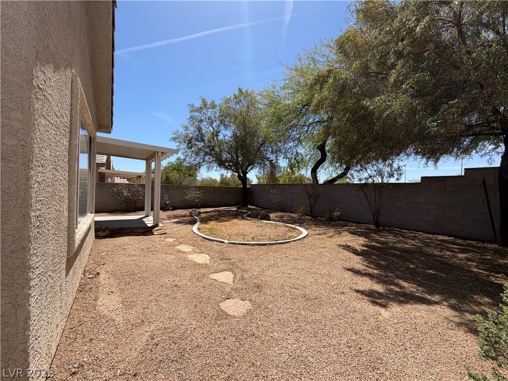 10975 Pumpkin Ridge Avenue Las Vegas, NV 89135 - Photo 12 of 13 A spacious backyard with mature trees provides ample shade and a cozy patio for outdoor relaxation.