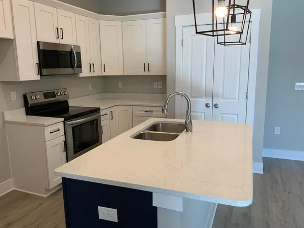 a kitchen with kitchen island a sink a stove and wooden cabinets