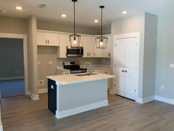 a kitchen with kitchen island stainless steel appliances a sink and wooden floor