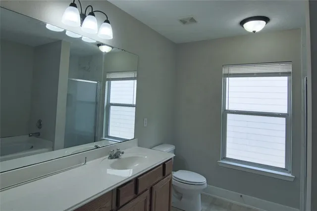 a bathroom with a granite countertop sink a toilet and a mirror