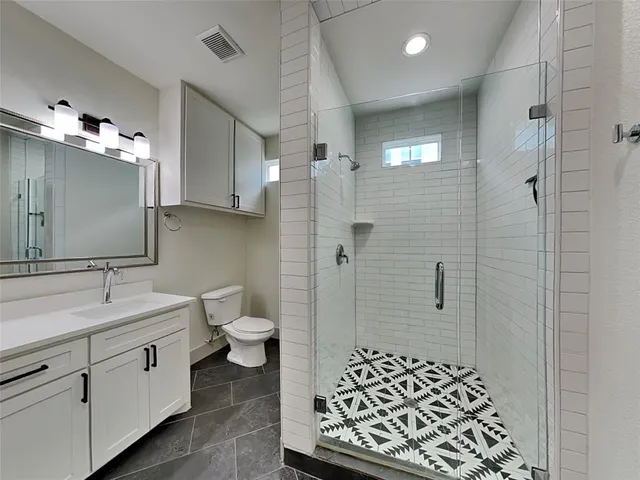 a spacious bathroom with a double vanity sink a toilet a mirror and shower