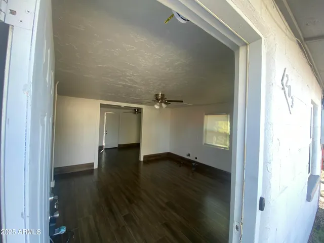 an empty room with wooden floor a ceiling fan and windows