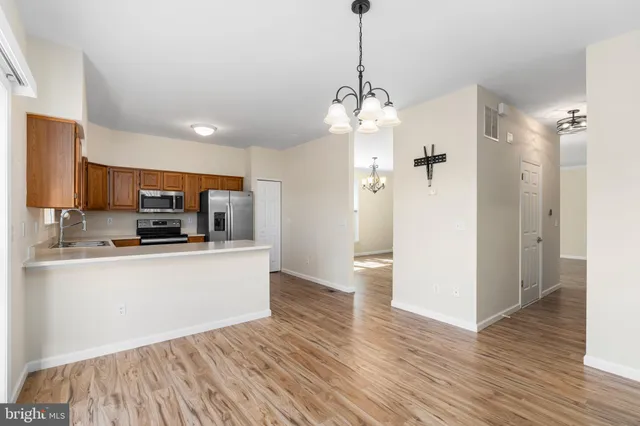 a view of a kitchen with stainless steel appliances granite countertop a refrigerator a stove a microwave and a wooden floor