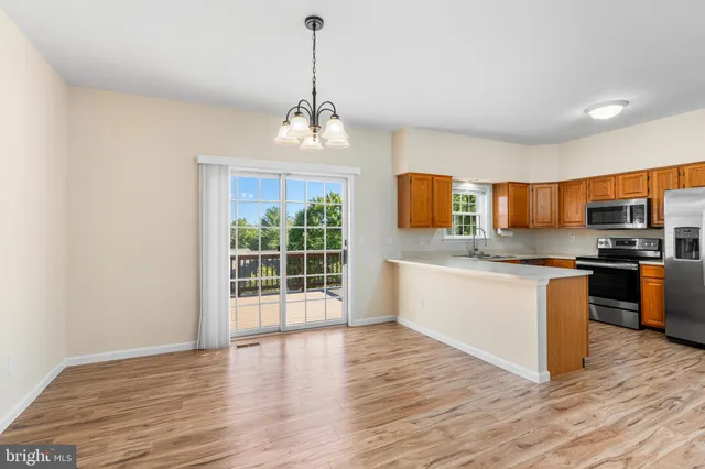 a kitchen with stainless steel appliances granite countertop a stove top oven a sink dishwasher a microwave oven and a wooden floor