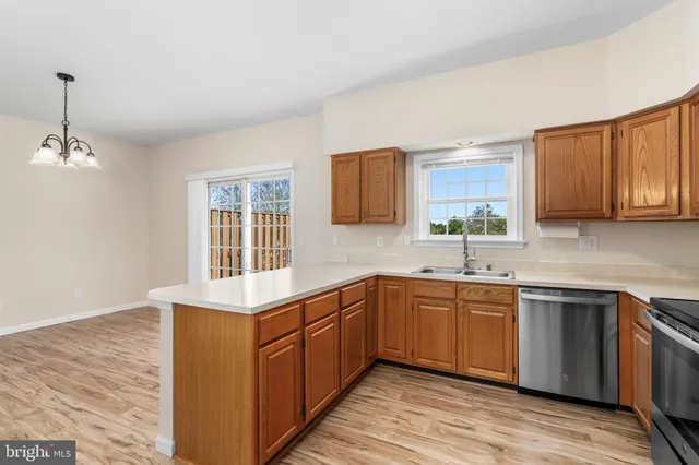 a kitchen with stainless steel appliances granite countertop wooden cabinets a sink and dishwasher a oven with wooden floors