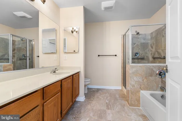 a bathroom with a granite countertop sink a mirror a bathtub and shower