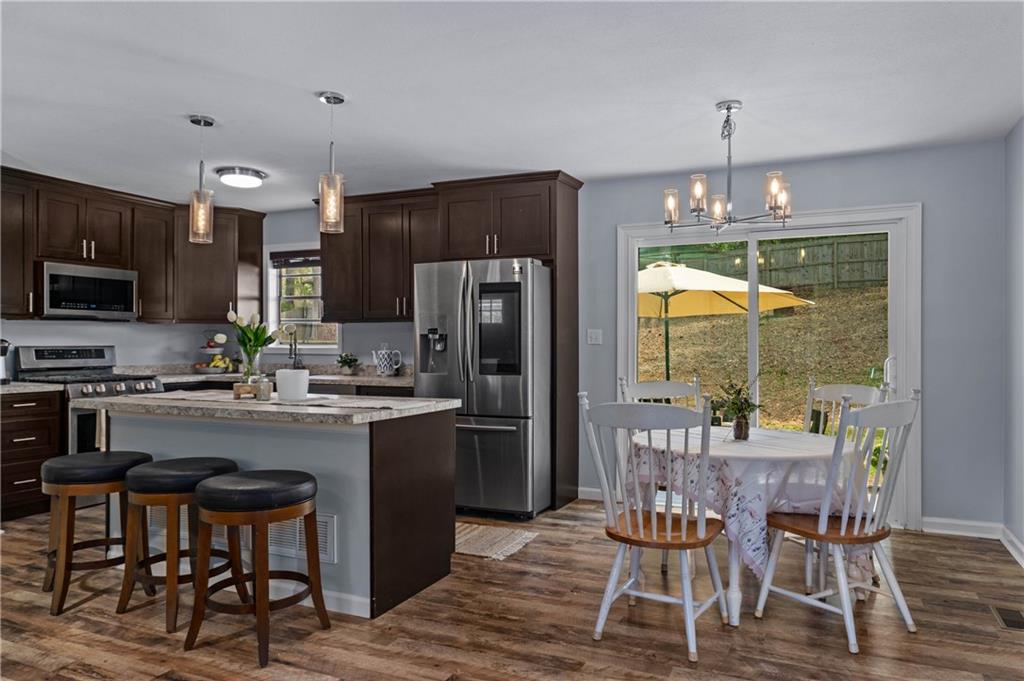 3990 Pine Mountain Road Northwest Kennesaw, GA 30152 - Photo 14 of 32 a kitchen with stainless steel appliances granite countertop a refrigerator a stove a kitchen island a dining table and chairs