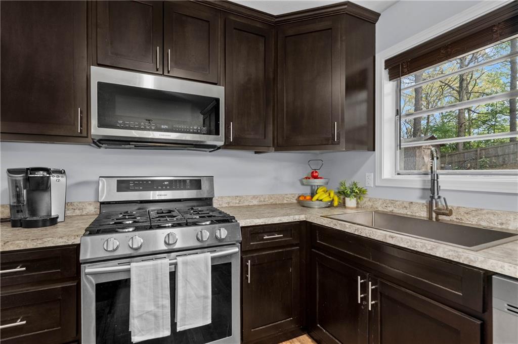 3990 Pine Mountain Road Northwest Kennesaw, GA 30152 - Photo 10 of 32 a kitchen with stainless steel appliances a stove a sink a microwave cabinets and a window