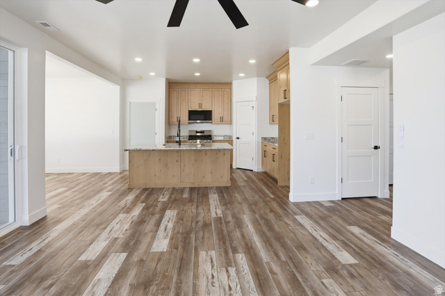 1315 West 3200 South, Unit 17 Perry, UT 84302 - Photo 7 of 58 Open-concept living space featuring wood-finish flooring, a kitchen island with stone countertops, light wood cabinetry, and recessed lighting