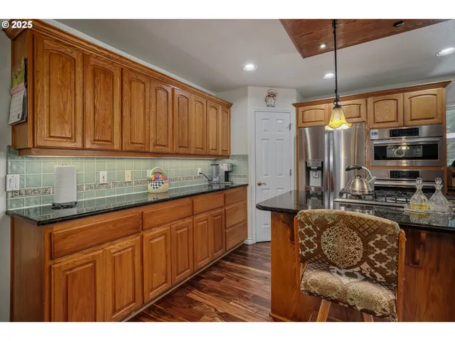 a kitchen with stainless steel appliances granite countertop a sink refrigerator and cabinets