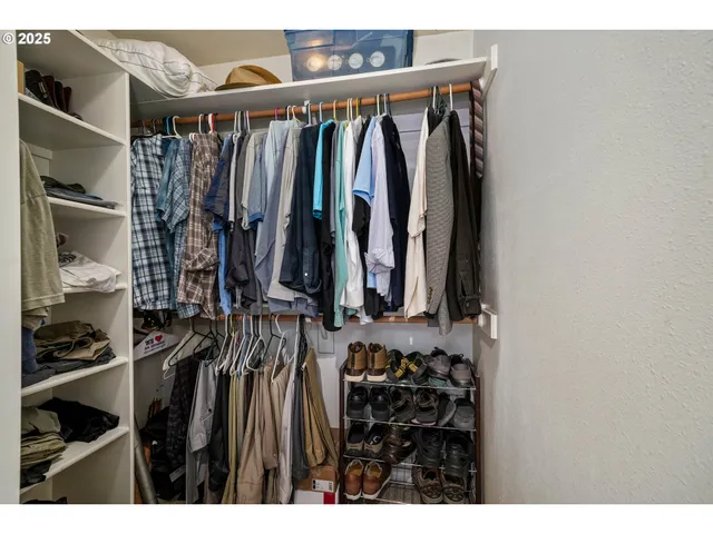 a view of walk in closet with clothes and shoes