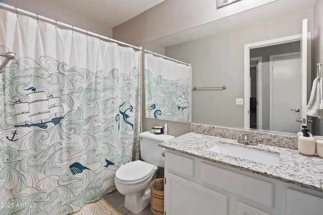 a bathroom with a granite countertop sink a toilet and a mirror