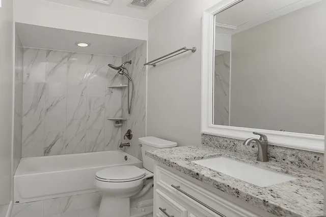 a bathroom with a granite countertop sink toilet and shower