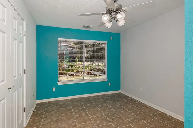 a view of an empty room with a window and a kitchen