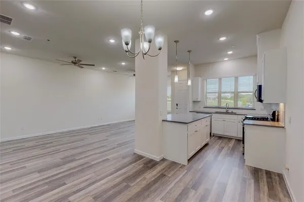 a large kitchen with granite countertop a large counter top a sink dishwasher and a stove with wooden floor