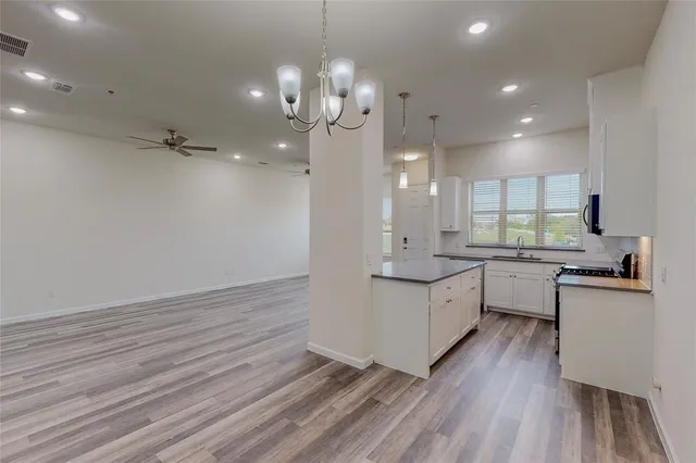 a large kitchen with granite countertop a large counter top a sink dishwasher and a stove with wooden floor